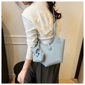 Close-up of light blue pebble grain leather bucket bag with matching mini charm on strap