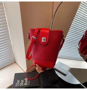 Detail of red pebbled leather bucket bag featuring a silver metal clasp and crossbody strap