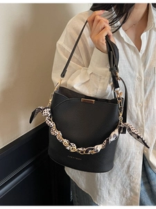 Minimalist black bucket bag with lychee texture and silk scarf chain, shown from front