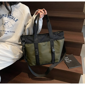 Detail of olive green nylon tote bag featuring black buckle straps and detachable strap