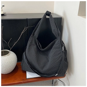 Detail of a black and white checkered canvas tote bag with adjustable shoulder straps