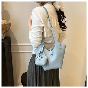 Detail of light blue bucket bag with pebble leather texture and matching mini pouch