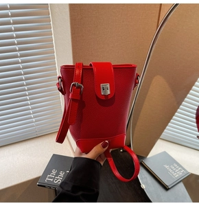 Detail of red lychee textured bucket bag with silver buckle and leather strap