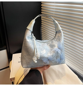 Detail of light blue embroidered bag with 3D mesh butterflies and floral texture