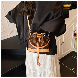 Back view of a mini monogram bucket bag with drawstring and leather strap on a model