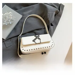 Detail of white gothic shoulder bag with metal cross pendant and silver rivet accents