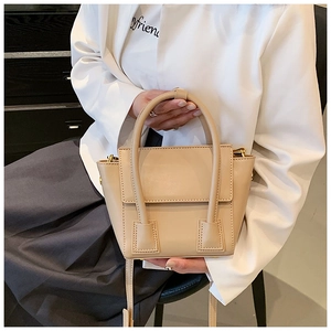Detail of beige PU leather handbag with dual top handles and adjustable shoulder strap