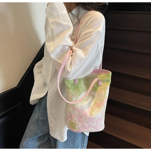 Detailed side view of the printed canvas tote bag worn by a model in casual attire
