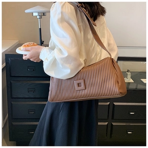 Brown pleated crossbody pillow bag with square buckle detail and a wide shoulder strap