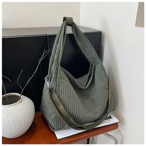 Detailed view of the dark green checkered canvas tote bag with adjustable shoulder straps
