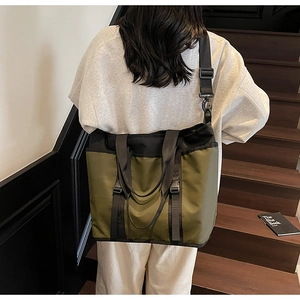 Detailed view of army green nylon tote bag worn as a shoulder bag on stairs