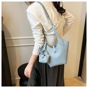Detail of light blue bucket bag with pebble leather texture and matching mini pouch