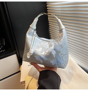 Détail du sac en dentelle bleu clair avec papillons en maille 3D et pendentif en perles