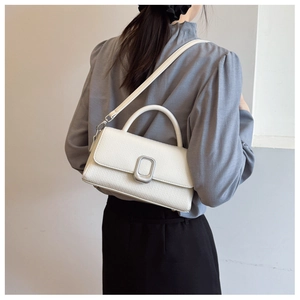 Detail of cream leather handbag with lychee texture and silver oval buckle closure