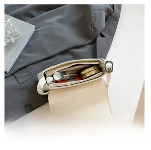 Internal view showing capacity for smartphone and makeup inside white leather crossbody bag