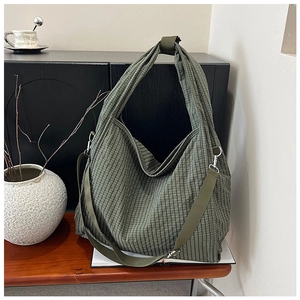 Detail of green plaid canvas tote showing thick fabric texture and metallic buckle strap