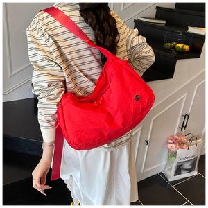 Detail of red nylon crossbody bag with adjustable strap and textured fabric finish