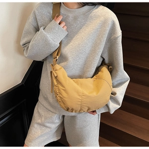 Close-up of a model wearing a light brown nylon crescent bag with adjustable strap