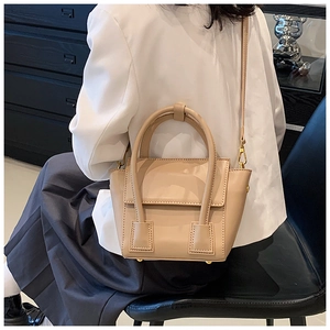 Detail of beige PU leather handbag showing round handle and metal protective feet