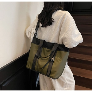 Detail showing the large army green commuter tote bag on a model in an indoor setting
