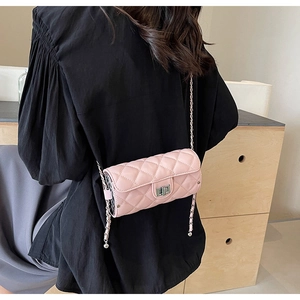 Close-up of pink quilted cylindrical bag with silver metal lock and chain strap detail