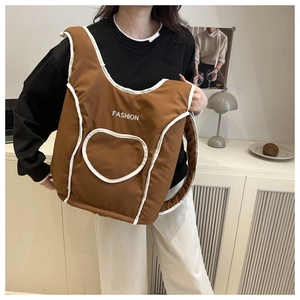 Detailed close-up of brown nylon bucket bag with white heart patch and fashion text