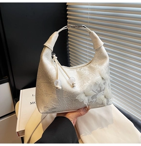 Detail of white lace handbag featuring 3D butterfly appliques and a unique metal handle