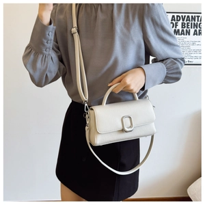 Detailed macro view of a white woven textured handbag with a silver metal clasp closure