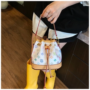 Detailed view of canvas bucket bag with colorful floral prints and leather trim details