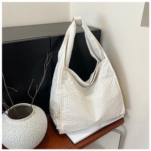 Detailed view of cream canvas tote bag with textured waffle fabric and knotted shoulder strap