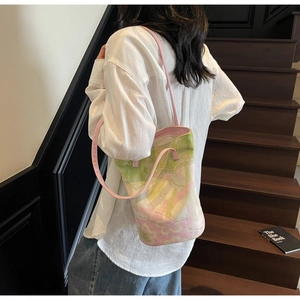 Detailed side view of floral canvas bucket bag with pink straps on a shoulder