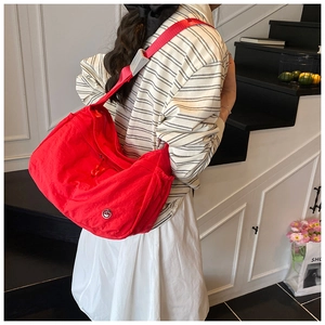 Detailed shot of large red nylon tote bag featuring wrinkled texture and adjustable strap