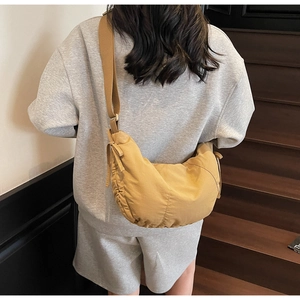 Detail of mustard yellow crescent bag featuring side drawstrings and wide fabric strap