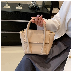 Close-up of elegant apricot PU leather handbag featuring gold buckles and dual round handles