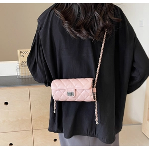 Detail of pink quilted crossbody bag with silver twist lock and woven chain strap on model