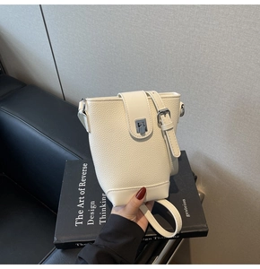 Detail of cream white leather bucket bag featuring a polished silver square metal clasp