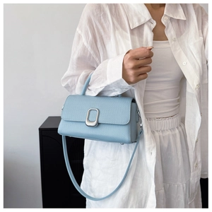 Detailed close-up of light blue leather handbag with woven texture and silver metal lock