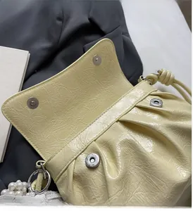 Détail du sac à bandoulière plissé jaune crème avec fermoir magnétique et texture brillante