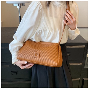 Detail of caramel striped shoulder bag with elegant pleated texture on minimalist outfit