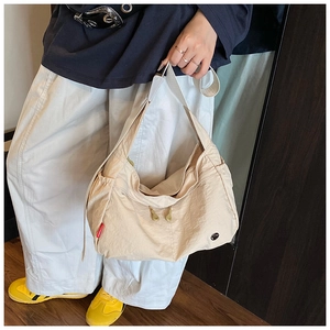 Detail view of the beige nylon hobo bag featuring its unique texture and red side label