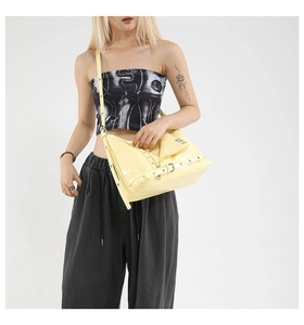 Detailed view of cream patent leather crossbody bag featuring biker jacket zip and studs
