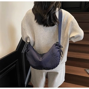 Detail of waterproof nylon crescent crossbody bag in navy blue with wide woven shoulder strap