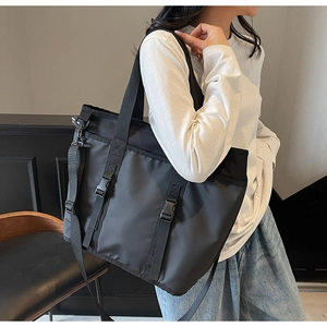 Detail of black high-capacity nylon tote bag with adjustable buckle straps and shoulder strap