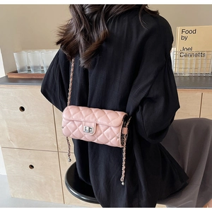 Detail view of pink quilted crossbody bag with silver clasp and woven chain strap