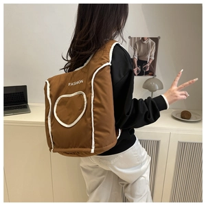Close-up of brown quilted puffer shoulder bag featuring heart stitching and white fashion text