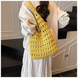 Detail of a bright yellow hand-knitted tote bag featuring a hollow mesh crochet design