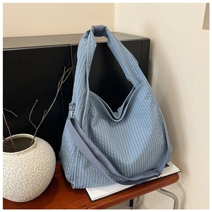 Close-up of blue micro-check canvas tote bag with wide strap and metal hardware