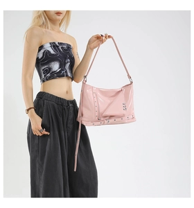 Detail of pink patent leather crossbody bag with silver studs and punk Y2K metallic rings