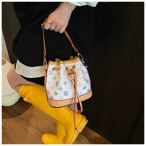 Close-up of white bucket bag with floral M print and brown leather trim details