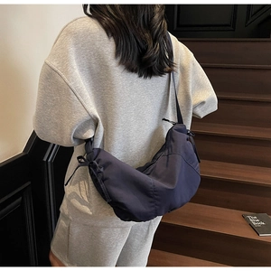 Detail of navy blue dumpling bag with drawstring bow detail on a casual crossbody strap